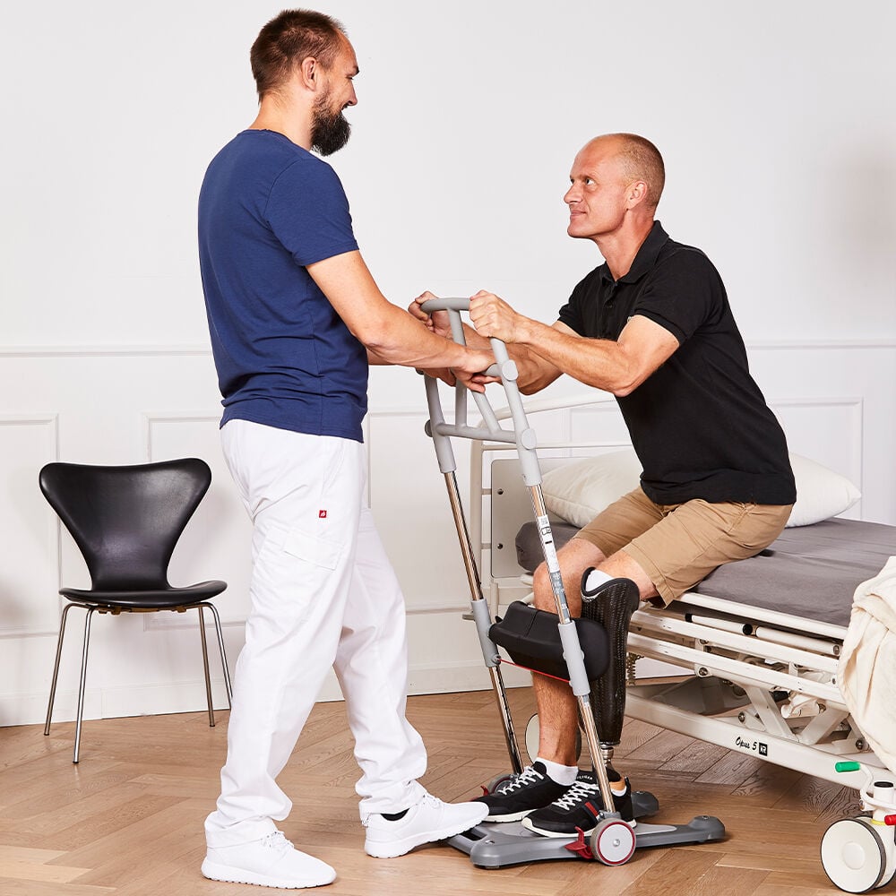 man being helped by nurse to stand up out of bed using molift quick raiser sit to stand aid