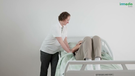 En vårdgivare ompositionerar en sängliggande person med hjälp av 4Direction DrawSheet Draglakan