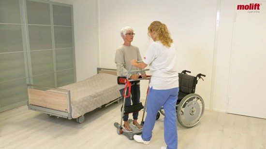 Einhändiger Transfer eines Nutzers von einem Bett in einen Rollstuhl, mit Hilfe des Raiser Gürtels.