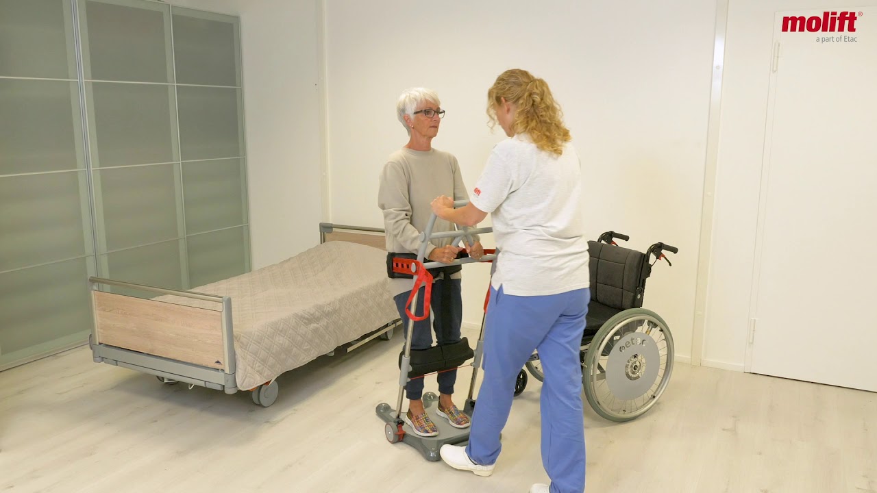 Överflyttning av en användare från en säng till en rullstol med hjälp av Raiser Belt, en vårdare