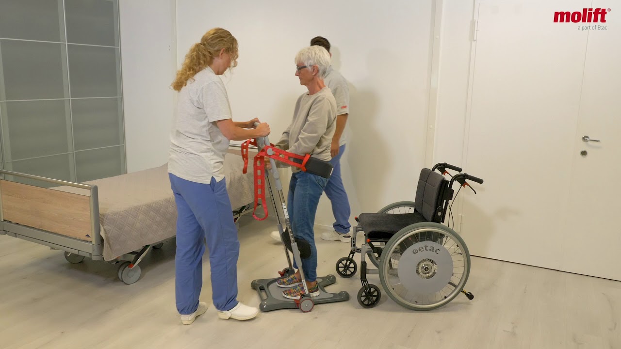 Sådan forflyttes fra kørestol til seng med Molift Raiser Pro & Safety strap med glidemuffe for to hjælpere.